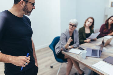 Geschäftsmann im Gespräch mit Kollegen während einer Besprechung im Büro. Reife Führungskraft hört sich während einer Präsentation die Vorschläge seines Teams an. - JLPSF13062