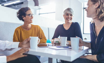 Ein Team von Geschäftsleuten bei einer lockeren Diskussion im Büro. Eine multiethnische Gruppe von Geschäftsleuten während einer Kaffeepause im Büro. - JLPSF13088