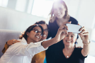 Gruppe von Geschäftsleuten teilen glückliche Momente im Büro. Geschäftsfrauen nehmen ein Selfie mit dem Handy. - JLPSF13093