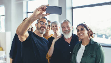 Business people taking selfie of themselves in the office. Successful business team taking selfie together at startup. - JLPSF13130