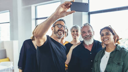 Happy group of businesspeople make selfie photo and smiling. Multi-ethnic business people taking selfie in office. - JLPSF13131