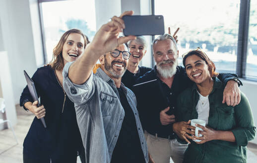 Fröhliche multiethnische Menschen im Büro lächelnd und die Aufnahme der selfie. Geschäftsmann, der selfie mit seinen Kollegen im Büro. - JLPSF13132
