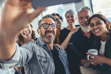 Group of happy people taking selfie in office. Start up entrepreneur at office taking selfie with his team. - JLPSF13136