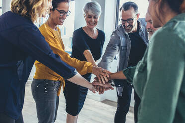 Business people stack hands together. Multi-ethnic group of business professionals putting their hands together as a symbol of teamwork. - JLPSF13137