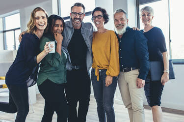 Cheerful business people standing together and laughing. Team of business professionals looking at camera and smiling. - JLPSF13145