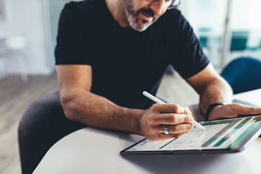 Geschäftsmann bei der Arbeit an einem Tablet-PC mit digitalem Stift. Geschäftsmann bei der Überprüfung eines Finanzberichts auf seinem digitalen Tablet. - JLPSF13150