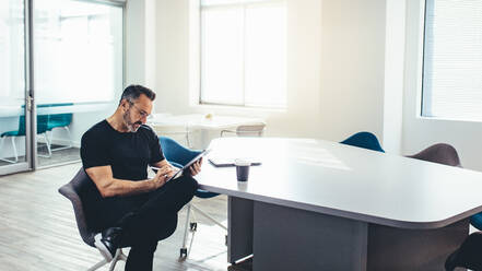 Mid erwachsenen Geschäftsmann arbeitet auf seinem digitalen Tablet in einem hellen Büro. Unternehmer mit seinem Tablet-Computer in einem modernen Büro Raum. - JLPSF13152