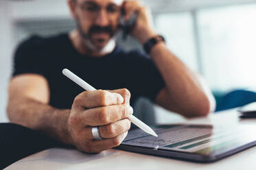 Businessman working on digital tablet and talking on cell phone. Businessman busy working in office , focus on digital tablet and stylus pen. - JLPSF13157