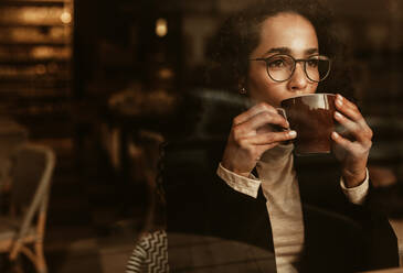 Frau mit Brille trinkt Kaffee und schaut weg. Frau sitzt im Café und trinkt eine Tasse Kaffee. - JLPSF13161