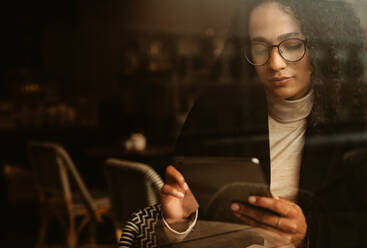 Geschäftsfrau sitzt in einem Café und benutzt ein digitales Tablet. Frau in einem Café und liest etwas auf ihrem digitalen Tablet. - JLPSF13166