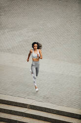 Blick von oben auf eine sportliche Frau beim Laufen im Freien. Frau in Sportkleidung beim Sprint am Morgen. - JLPSF13219