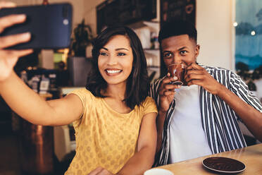 Junge Frau nimmt Selfie mit ihrem Freund trinken Kaffee in einem Café. Junge Freunde sitzen zusammen in einem Café und nehmen Selfie. - JLPSF13268