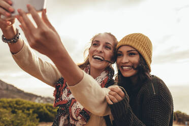 Two women taking selfie while hiking. Female friends on hiking trip taking a selfie for her social media content. - JLPSF13310