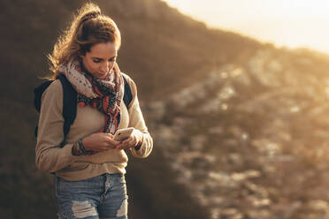 Junge Frau auf Wandertour, die ihr Smartphone benutzt. Wanderin, die ihren Status in den sozialen Medien aktualisiert. - JLPSF13331