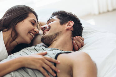 Young couple lying in bed together. Romantic couple in love looking at each other and smiling. - JLPSF13346