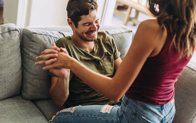 Woman sitting on top of her boyfriend on sofa. Playful couple having a fun at home. - JLPSF13371