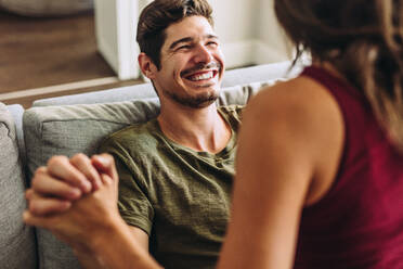 Cheerful young man sitting with her girlfriend at home. Couple enjoying free time at home. - JLPSF13372