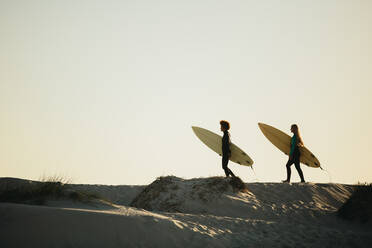 Zwei Surferinnen, die mit ihren Surfbrettern auf das Meer zugehen. Freundinnen beim Surfen im Meer. - JLPSF13440