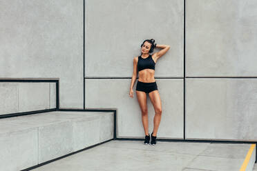 Woman resting after workout. Full length of sporty young woman relaxing after running exercise. - JLPSF13481