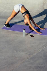Flexible junge Frau beim Üben der Yoga-Pose des nach unten gerichteten Hundes. Frau in Sportkleidung beim morgendlichen Stretching-Training. - JLPSF13508