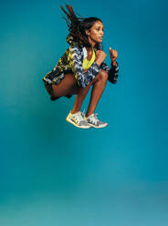 Sport Frau springt hoch. gesunde junge Fitness Frau tun Übung über blauen Hintergrund. - JLPSF13570