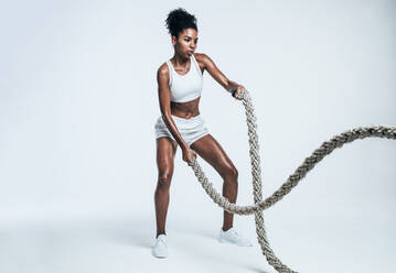 Fitness woman exercising with battle rope