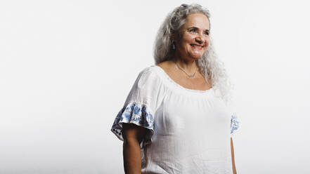 Lächelnde Frau mit weißen Haaren isoliert auf weißem Hintergrund. Ältere Frau mit einem schönen Lächeln, die wegschaut. - JLPSF13621