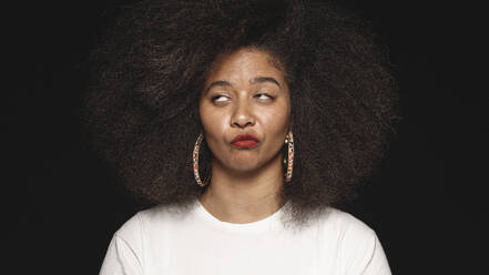 Afroamerikanische Frau mit Afrofrisur isoliert auf schwarzem Hintergrund. Nahaufnahme einer Frau, die Gesichter macht und wegschaut. - JLPSF13632