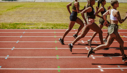 Weibliche Athleten, die ein Rennen auf der Bahn laufen. Frauen, die an einem Rennen im Leichtathletikstadion teilnehmen. - JLPSF13732