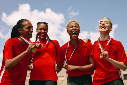 Frauenfußballmannschaft mit Medaillen, die einen Sieg feiern. Aufgeregte Frauenfußballmannschaft, die nach dem Gewinn der Meisterschaft vor Freude schreit. - JLPSF13736