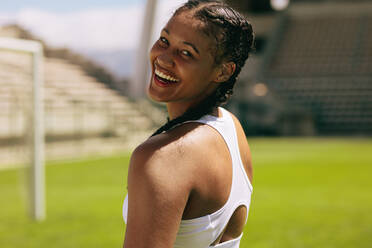 Side view of a smiling athletic woman looking at her biceps during