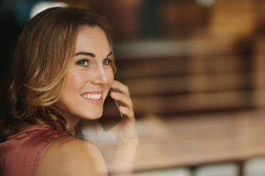 Closeup of a woman talking over mobile phone looking away. Portrait of a smiling woman holding a phone to her ear. - JLPSF13775