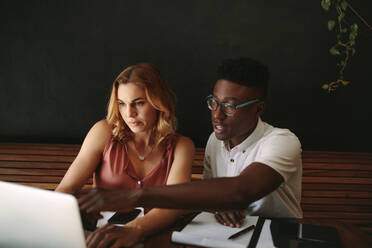 Man and woman discussing work at a coffee shop. Entrepreneurs sitting at a coffee shop working on a laptop computer. - JLPSF13778