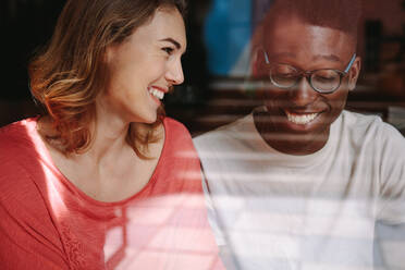 Smiling woman looking at her friend at a coffee shop. Friends sitting at a coffee shop and talking. - JLPSF13787