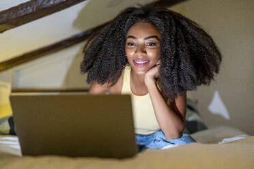 Young woman watching movie on laptop in bedroom - DLTSF03278