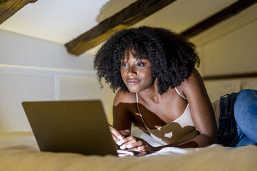 Afro-Frau sieht sich im Schlafzimmer zu Hause einen Film auf dem Laptop an - DLTSF03279