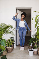 Happy young woman with house keys standing in doorway - EBBF06627