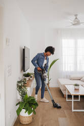 Woman cleaning living room with vacuum cleaner at home - EBBF06672