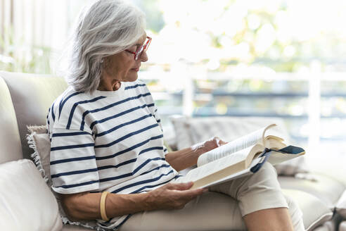 Frau liest ein Buch auf dem Sofa zu Hause - JSRF02252