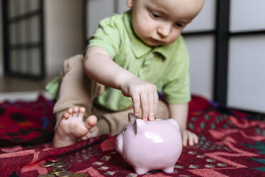 Baby boy putting coin in piggy bank - EYAF02253