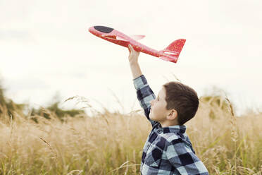 Boy flying toy airplane at field - ONAF00180