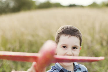 Cute boy playing with toy airplane in field - ONAF00182