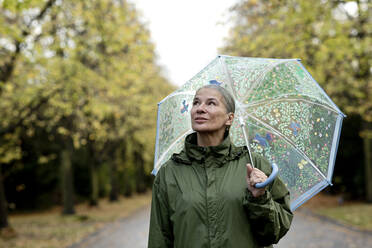 Nachdenkliche ältere Frau mit Regenschirm - FLLF00806