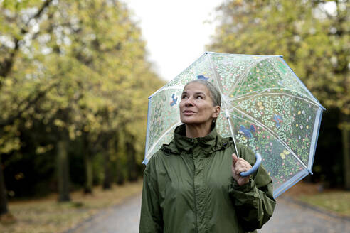 Thoughtful senior woman holding umbrella - FLLF00806