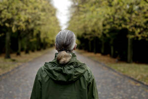 Ältere Frau mit grauem Haar trägt einen Regenmantel mit Kapuze - FLLF00807
