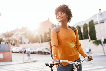 Lächelnde junge Frau mit Fahrrad auf der Straße - EBBF06684