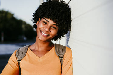 Smiling woman with short hair leaning on wall - EBBF06696