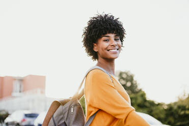 Afro smiling woman with backpack at sunset - EBBF06697