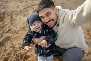 Happy father taking selfie with son at beach - ANAF00244