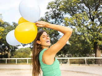 Fröhliche Frau hat Spaß mit Luftballons am Fußweg - AMRF00097